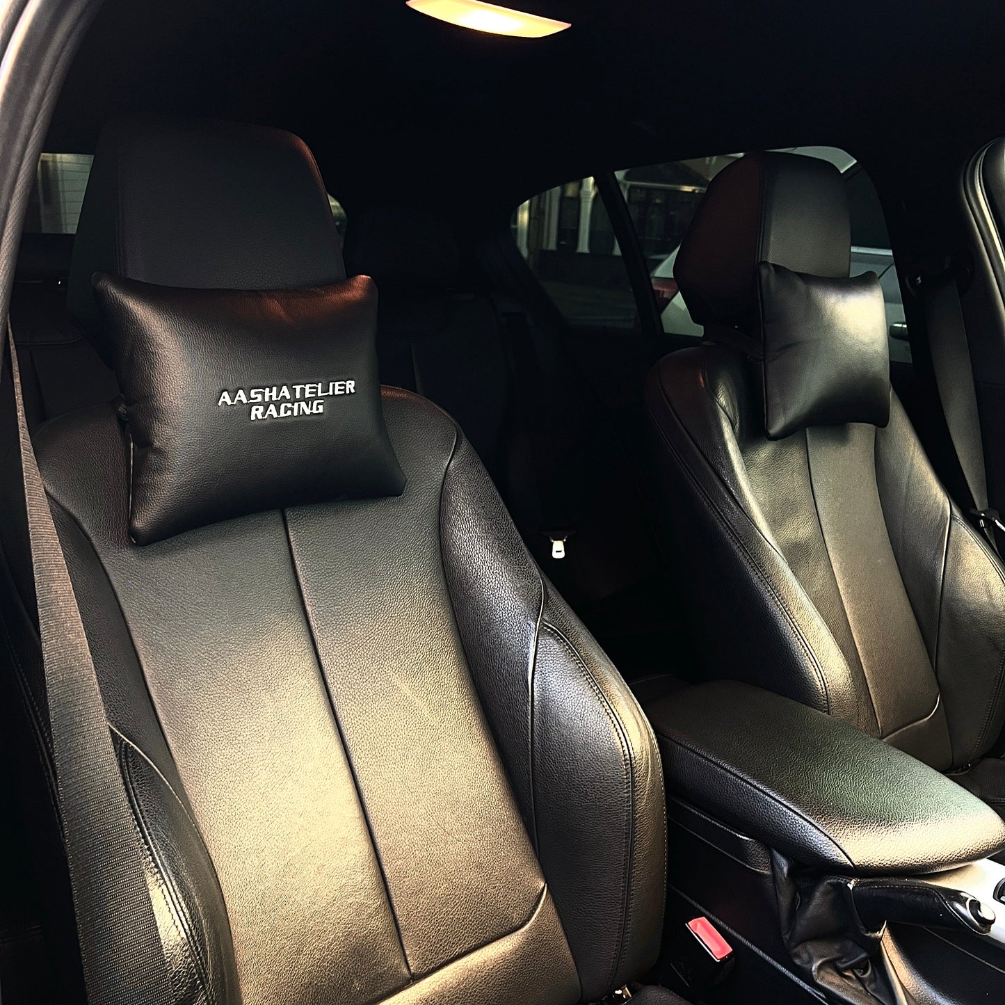 Car interior with black leather seats and headrests, featuring personalised car embroidered headrests with names and logos.